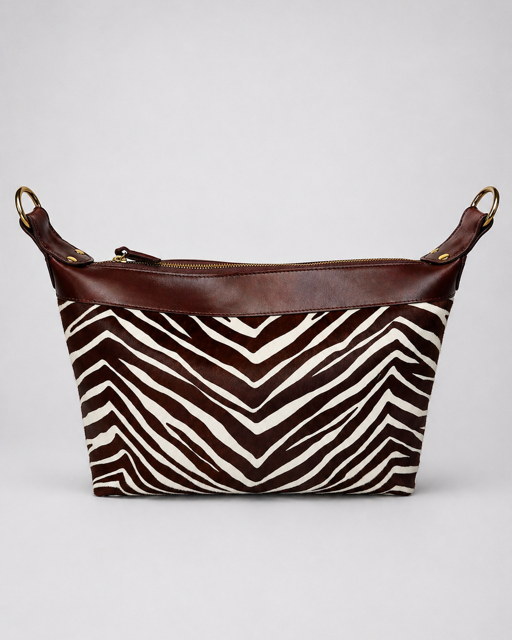 Zebra print bag with brown leather accents on a white background